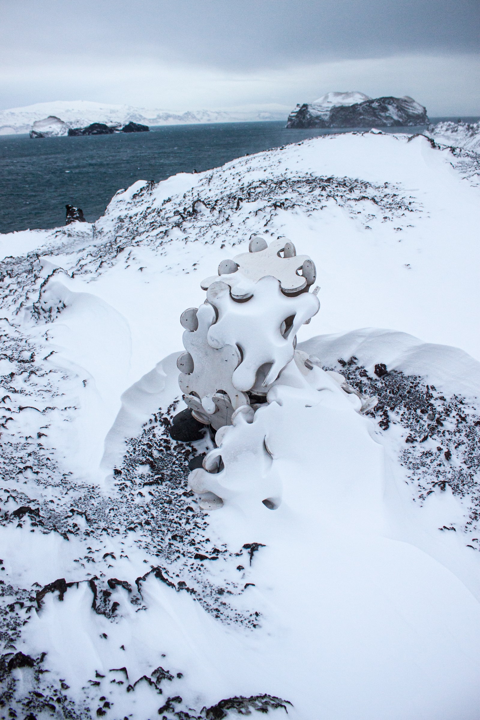 Sculpture System 5 snow-packed on the Eldfell lava field, the outer islands of Vestmannaeyjar behind, December 2009